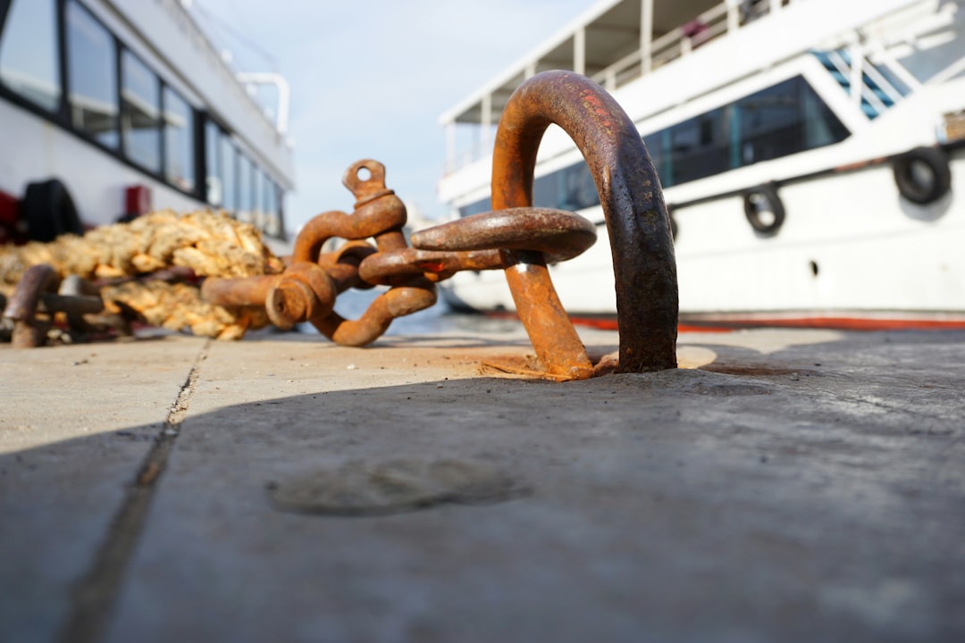 Various anchoring hardware, including galvanized chains, shackles, and a concrete anchor, laid out on a wooden dock surface - floating dock tie downs Various anchoring hardware, including galvanized chains, shackles, and a concrete anchor, laid out on a wooden dock surface - floating dock tie downs