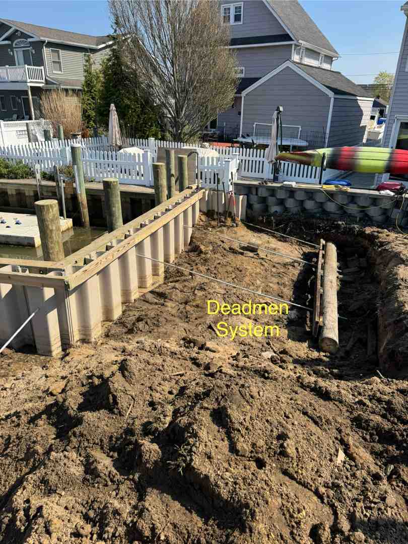 Massapequa NY new vinyl bulkhead under construction with driven piles, tie-rods, and concrete cap; sunny day; crisp focus on craftsmanship - Coastal resiliency projects Massapequa NY new vinyl bulkhead under construction with driven piles, tie-rods, and concrete cap; sunny day; crisp focus on craftsmanship - Coastal resiliency projects