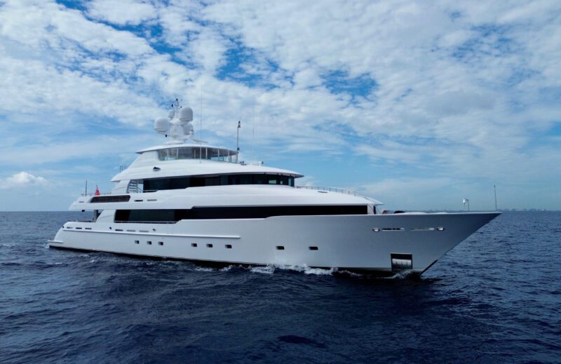 A large Delta Marine Noverra luxury yacht sails on calm ocean water under a partly cloudy sky.