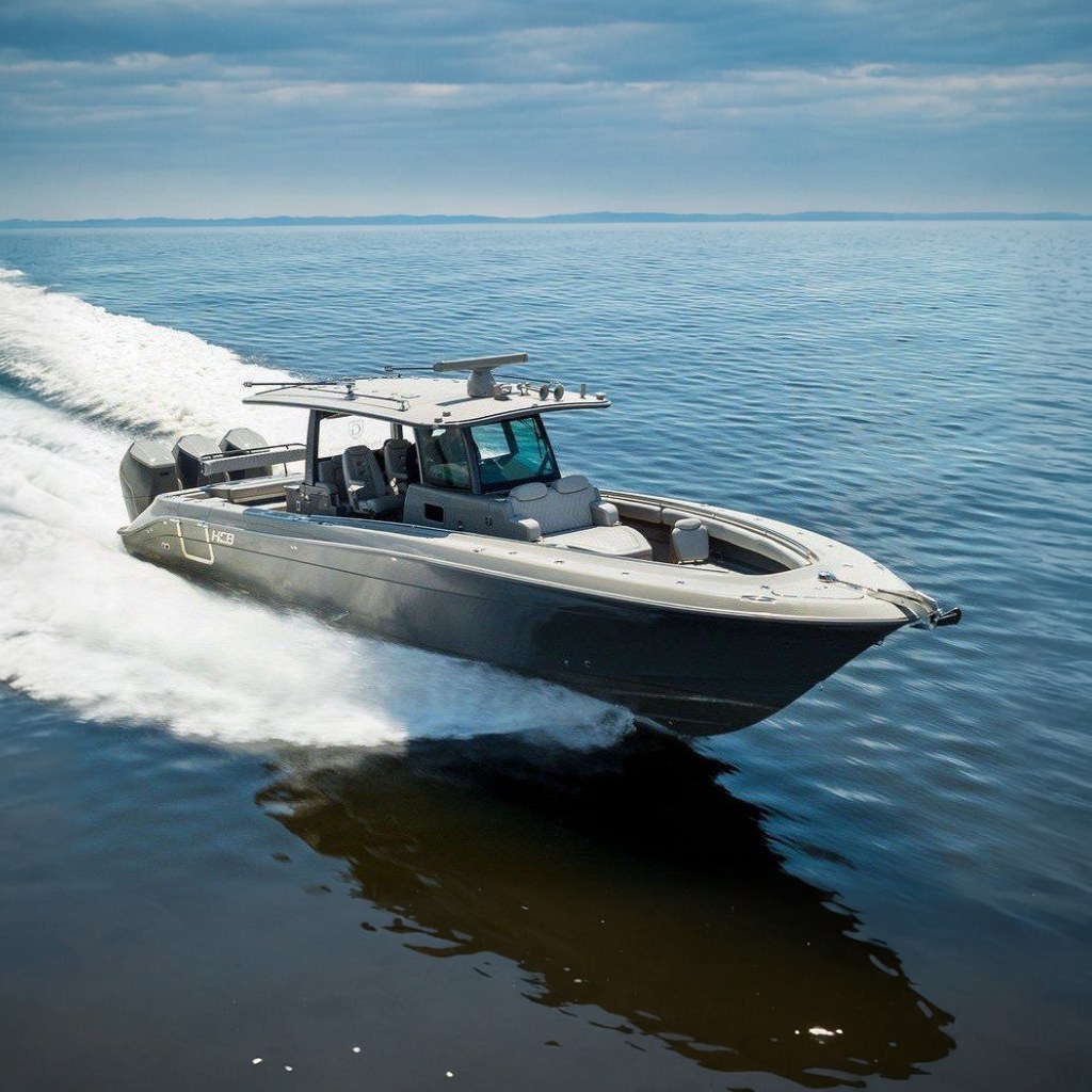 A 2023 HCB 42 Lujo speeds across calm water under a cloudy sky.
