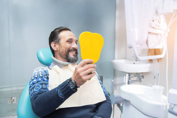Man in a dental chair. Man in a dental chair. Person smiling and holding mirror. Make your smile perfect. Middle-aged man smiling confidently in a dental office, sitting comfortably in the chair while talking with a dentis stock pictures, royalty-free photos & images