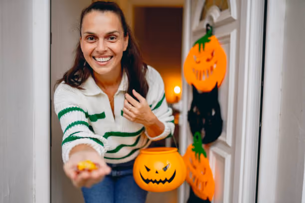 Trick or treat Mid adult woman getting ready for trick or treat WOMAN GIVING OUT HALLOWEEN CANDY stock pictures, royalty-free photos & images