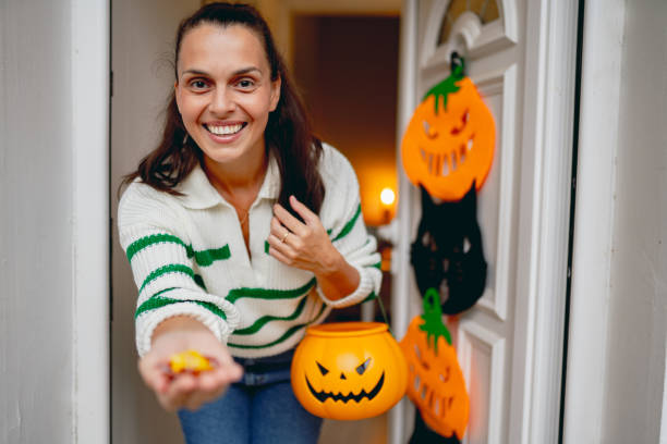 Trick or treat Mid adult woman getting ready for trick or treat WOMAN GIVING OUT HALLOWEEN CANDY stock pictures, royalty-free photos & images