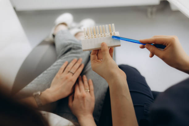 Smile and white teeth of a young woman. Matching the shades of the implants or the process of teeth whitening. Smile and white teeth of a young woman. Matching the shades of the implants or the process of teeth whitening. Dentist showing a patient shade options for whitening stock pictures, royalty-free photos & images