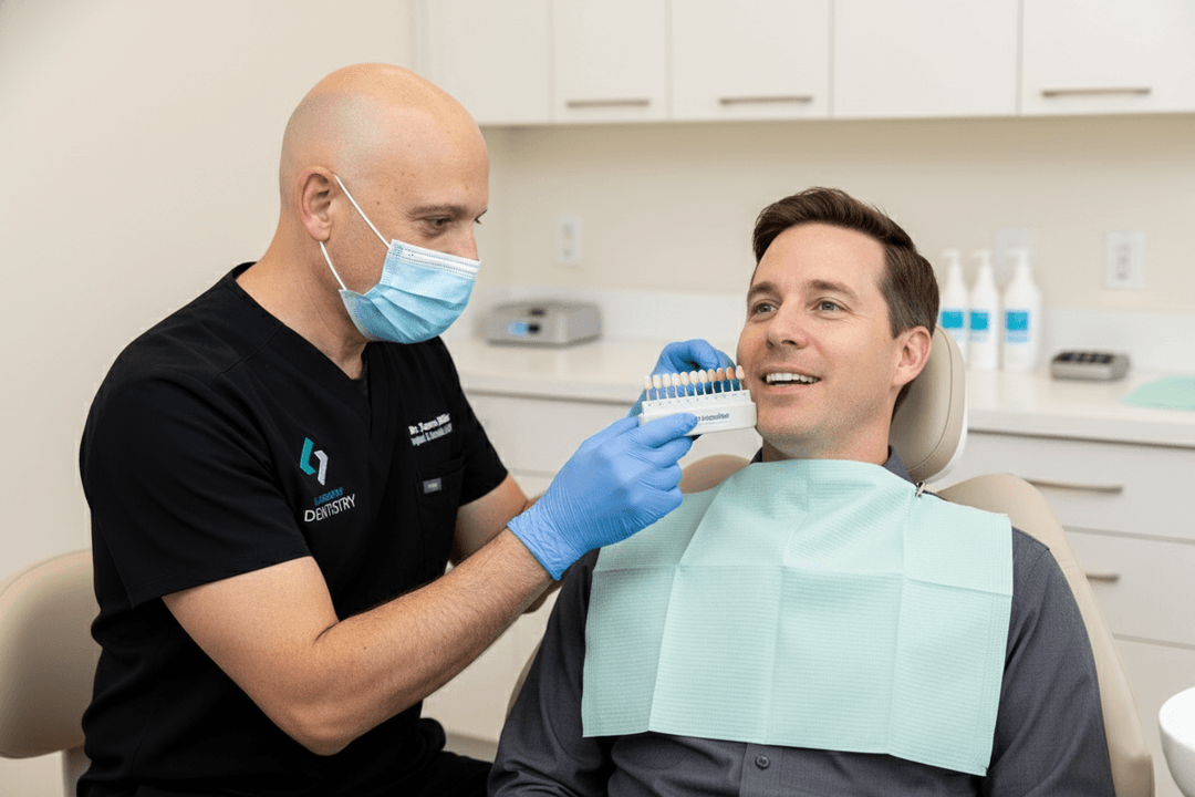 A Clairemont Dentistry dentist shows a tooth shade guide to a smiling patient during a cosmetic dental consultation in a clean exam room.