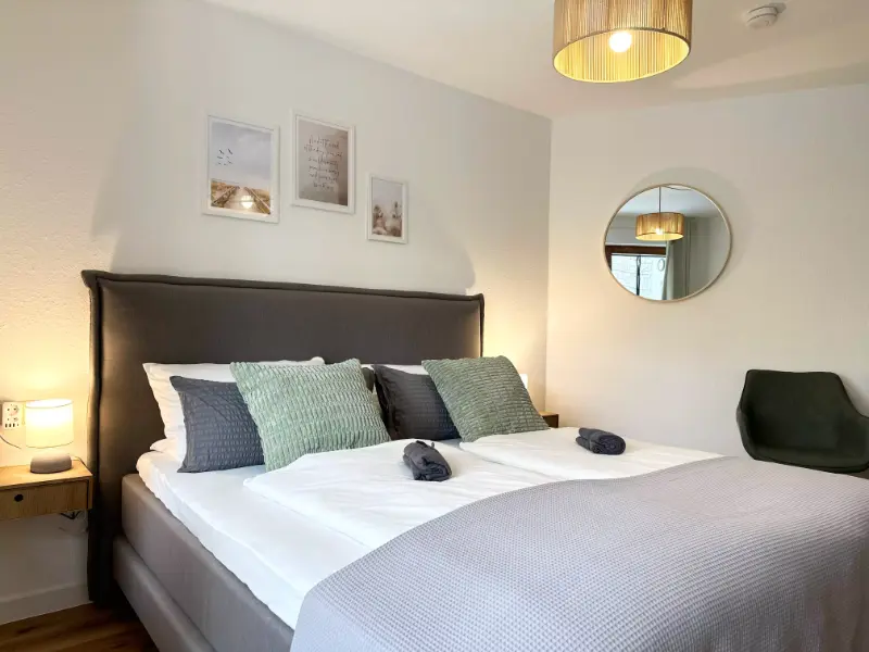 Schlafzimmer mit einem Bett und einem Spiegel, ideal für einen Luxusurlaub in Uhldingen Mühlhofen am Bodensee.