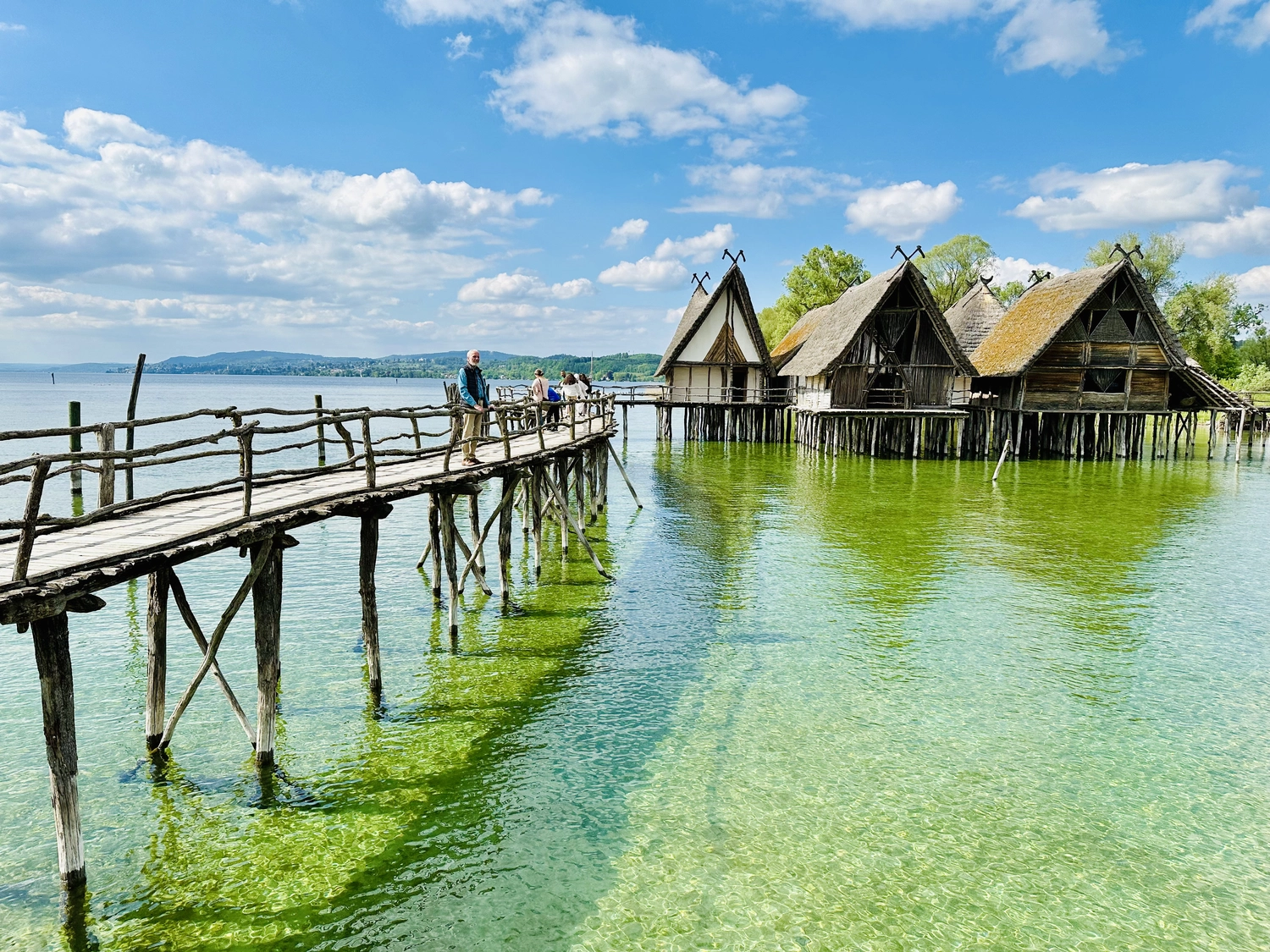 Holzbrücke über Wasser mit Hütten am Ufer in Uhldingen Mühlhofen, ideal für Luxus-Ferienwohnungen am Bodensee.