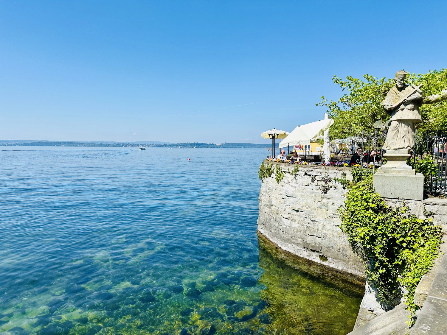Holzbrücke über Wasser mit Hütten am Ufer in Uhldingen Mühlhofen, ideal für Luxus-Ferienwohnungen am Bodensee.