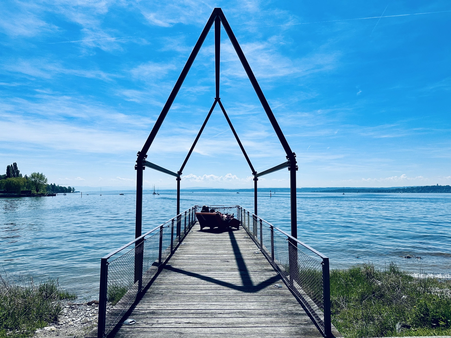 Holzbrücke über Wasser mit Hütten am Ufer in Uhldingen Mühlhofen, ideal für Luxus-Ferienwohnungen am Bodensee.