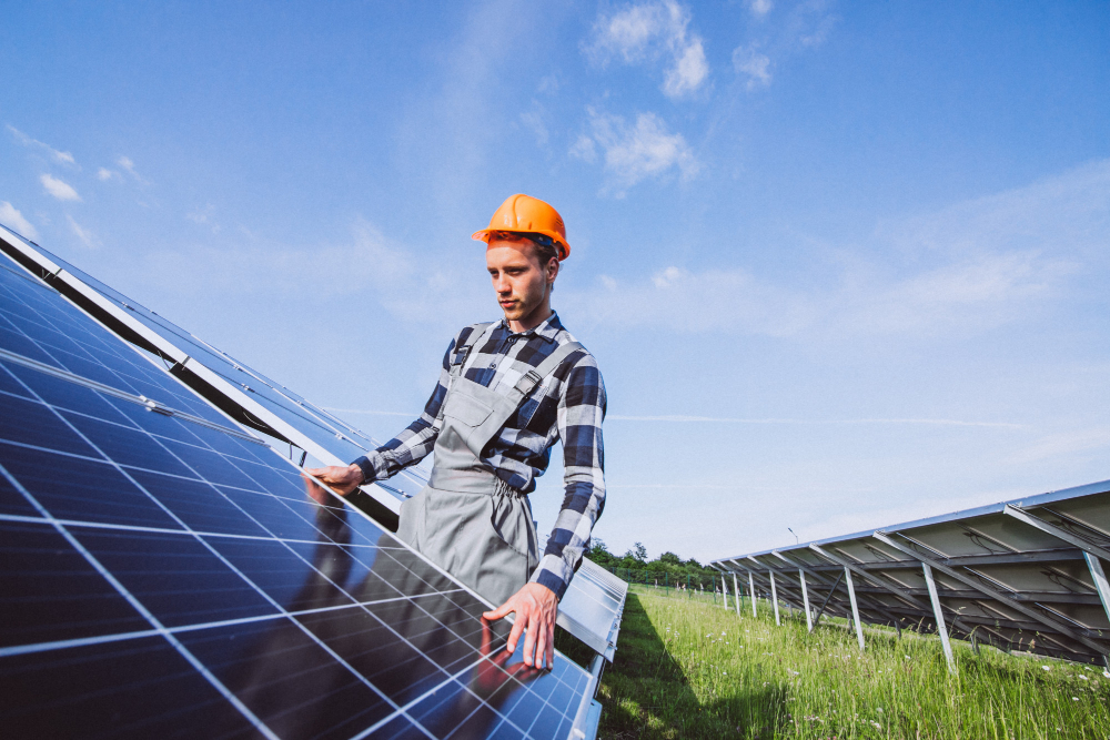 A solar engineer in orange hard hard checking the solar panels