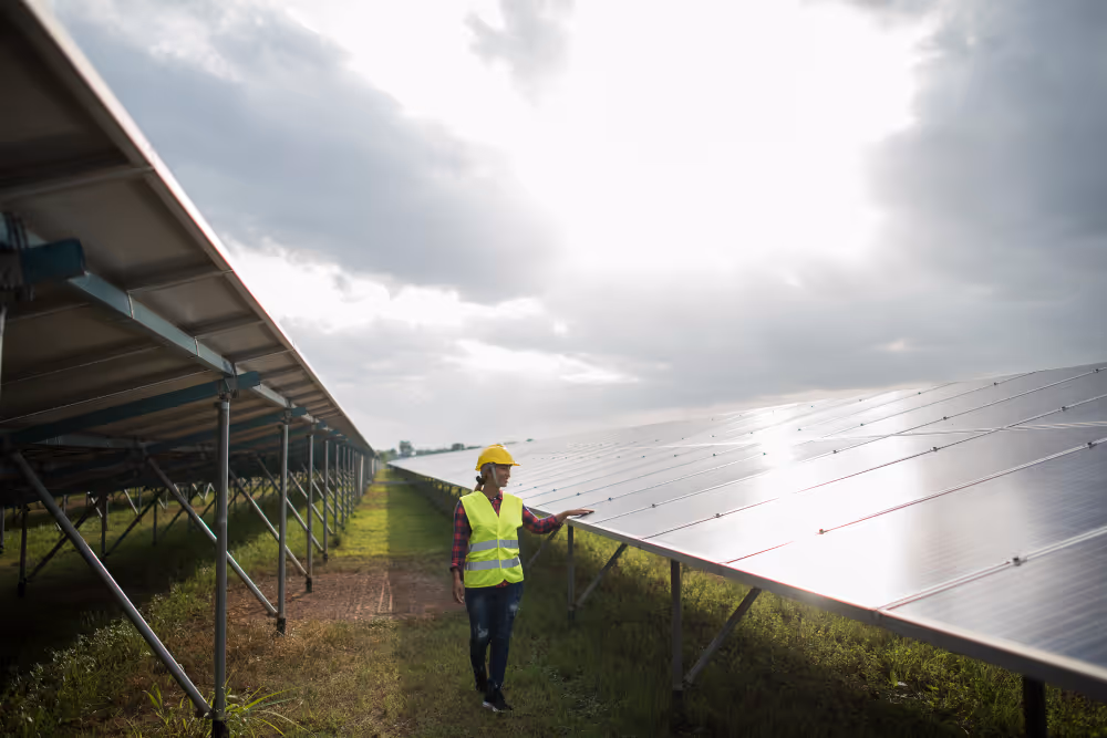 Man worker in the field by the solar panels