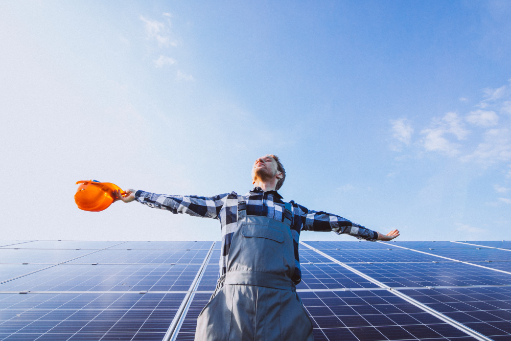 Man worker in the field by the solar panels