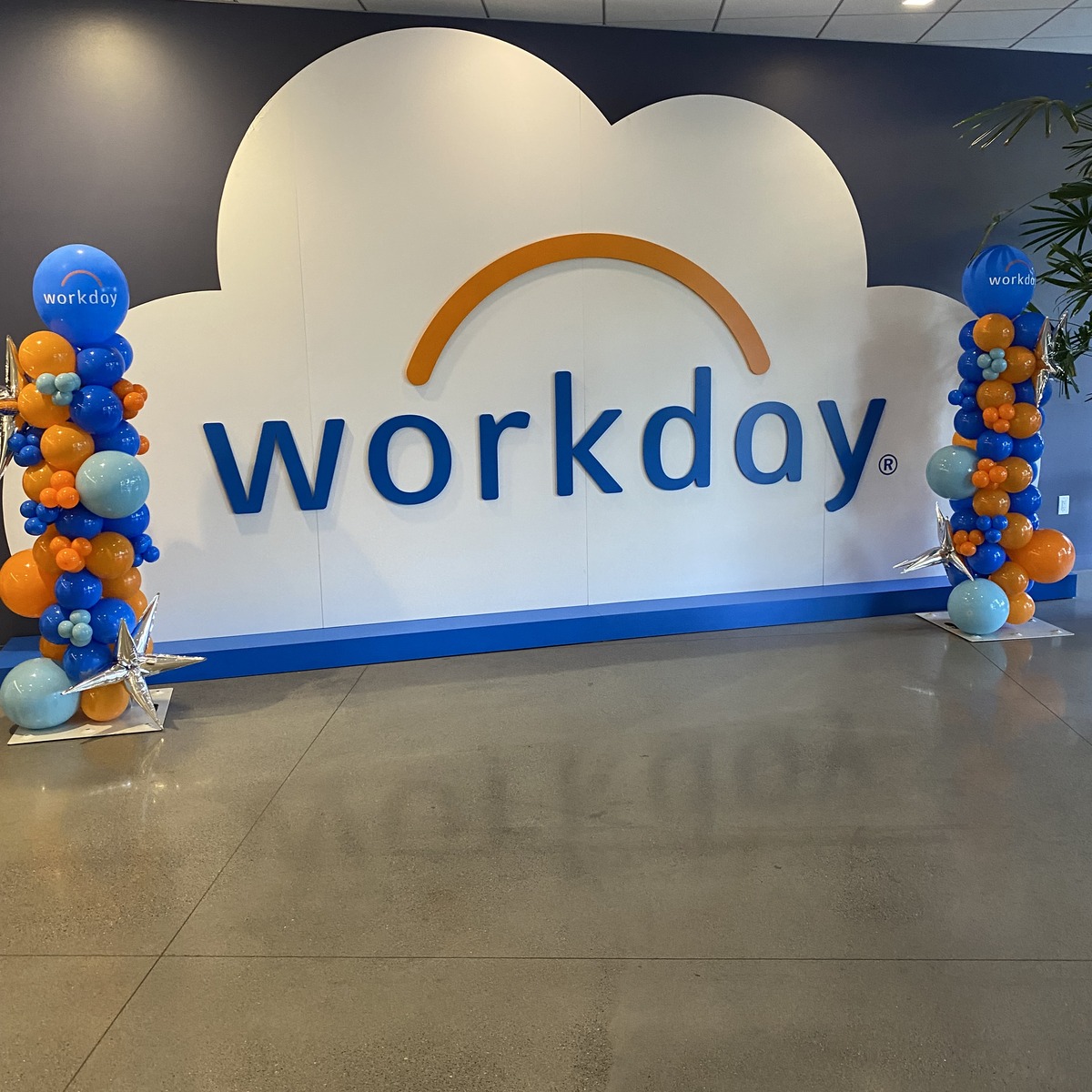 Corporate lobby with branded balloon columns framing a company logo wall