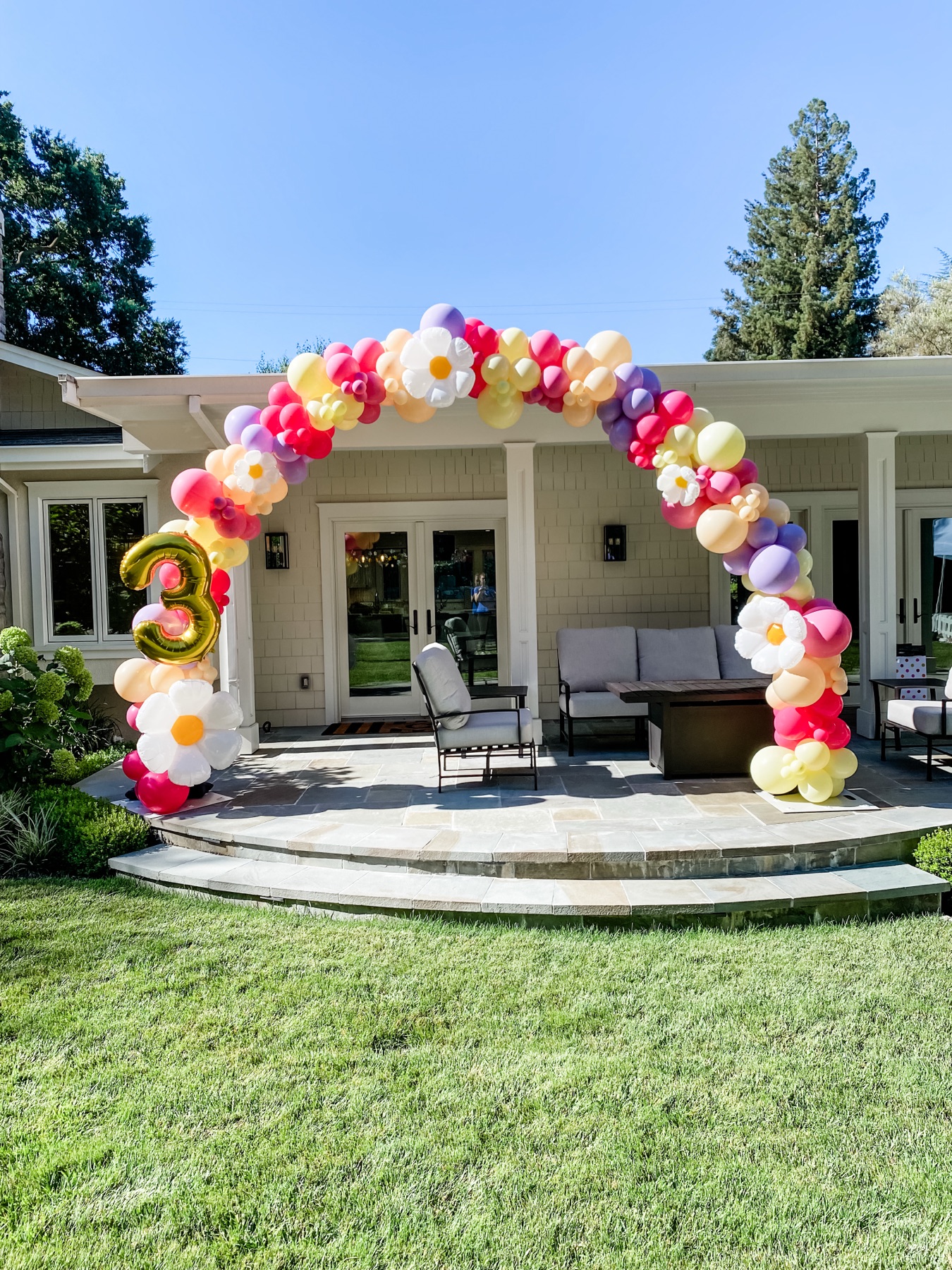 Colorful backyard balloon arch over a patio for a birthday party