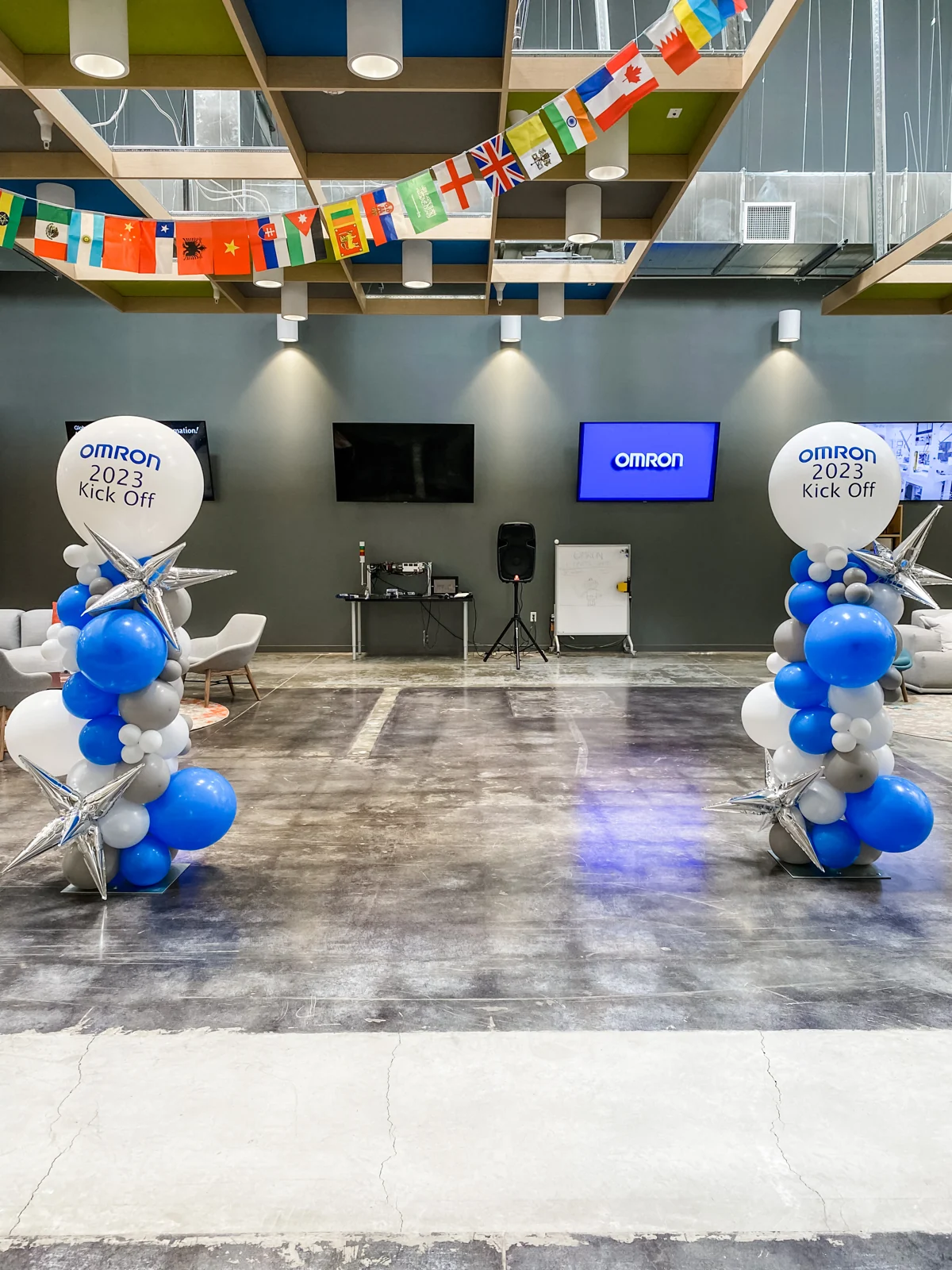 Blue and white balloon columns with silver stars and branded toppers at a company event
