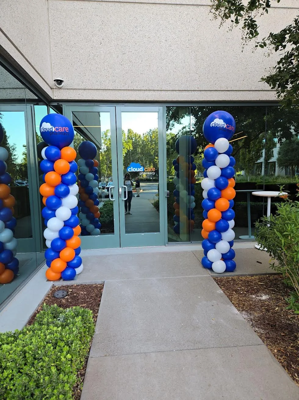 Blue, orange and white spiral balloon columns flanking a CloudCare Pharmacy entrance