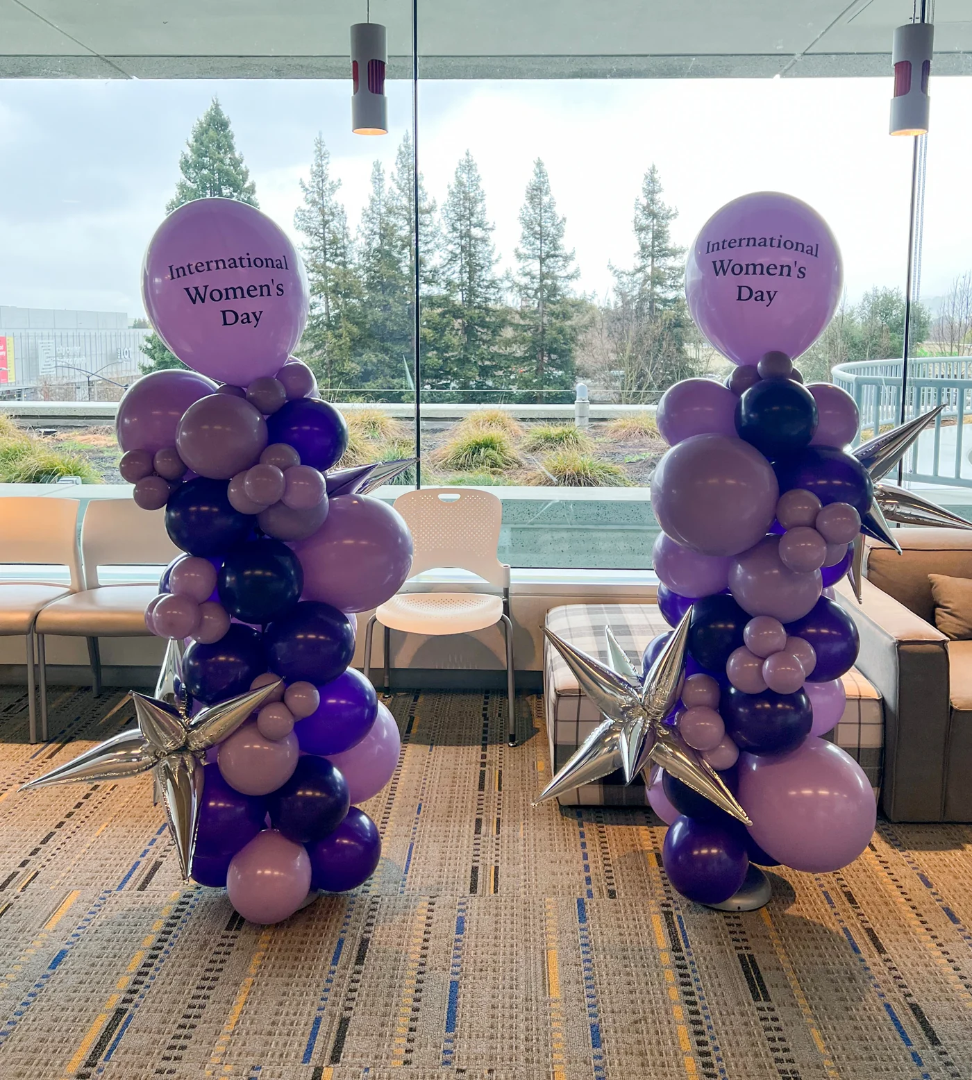 Purple balloon columns with International Women’s Day toppers beside event tables