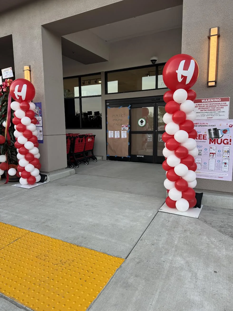 Red and white balloon columns with branded red toppers at an entrance