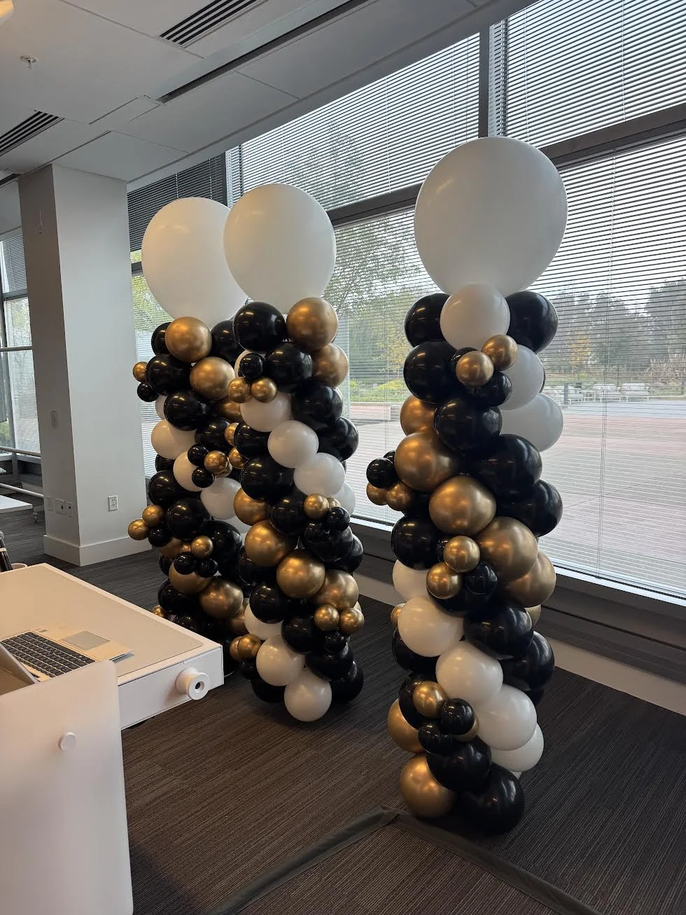 Black, gold and white balloon columns with large white toppers