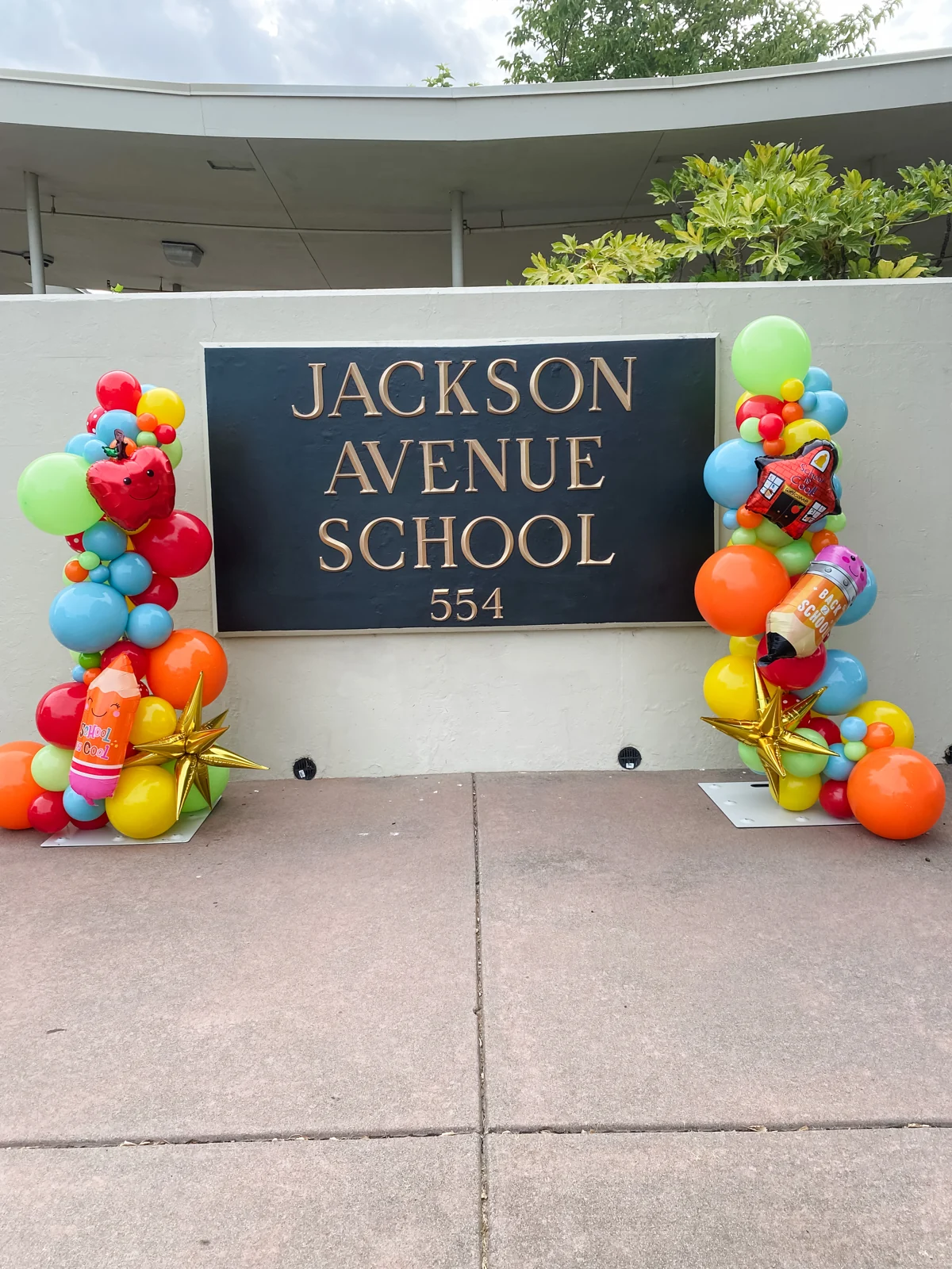 Colorful organic balloon columns framing the Jackson Avenue School sign