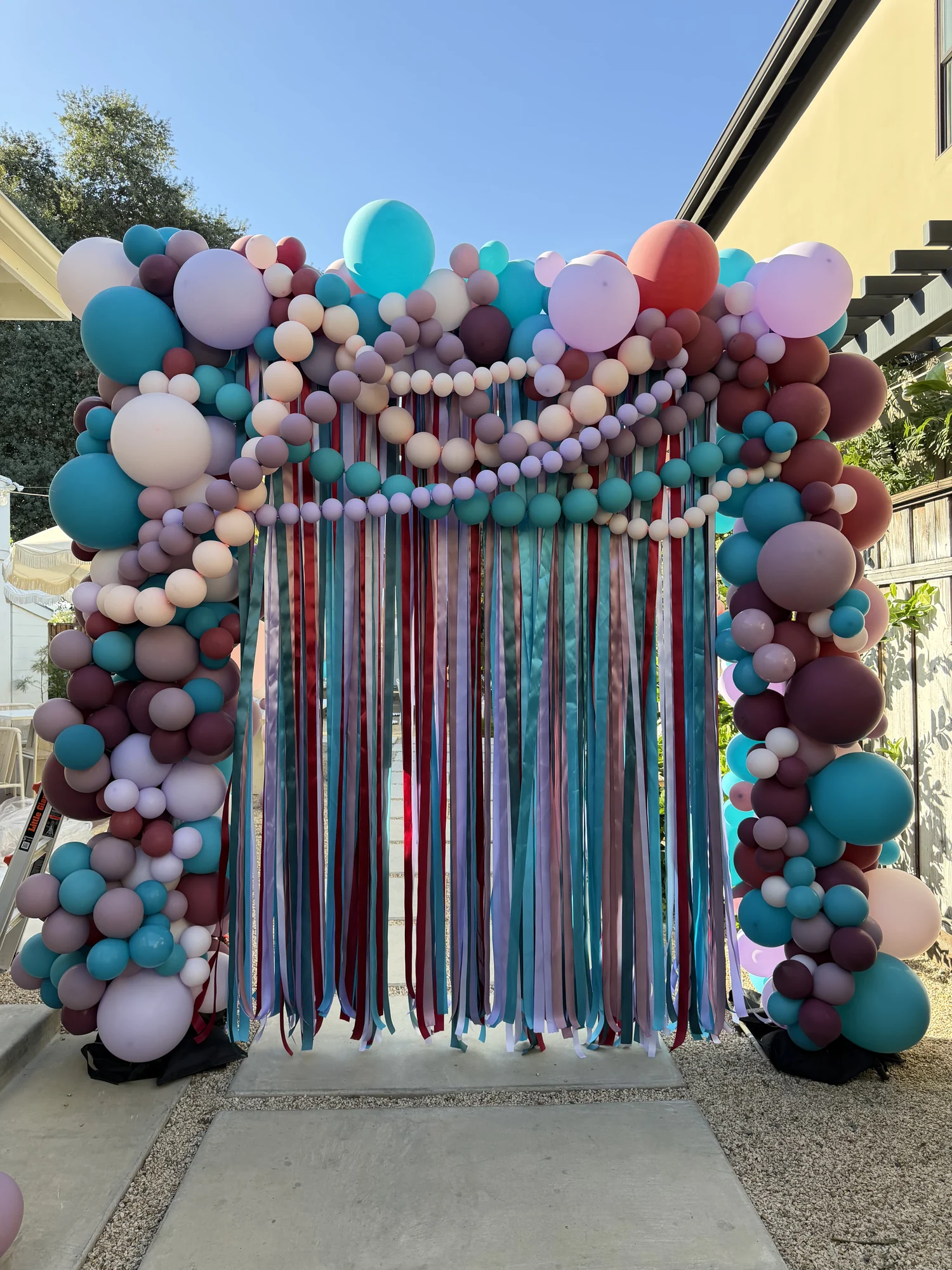 Teal, lavender, blush and burgundy balloon backdrop with flowing ribbons