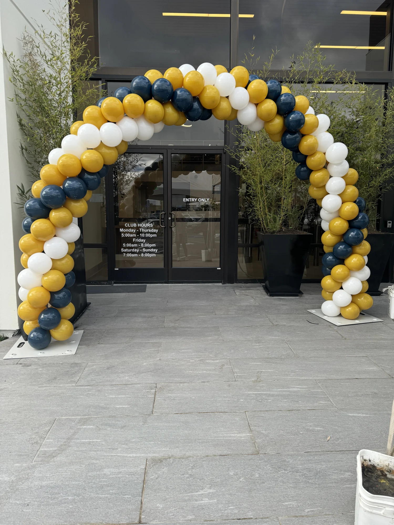 Navy, white and gold spiral balloon arch framing a business entrance