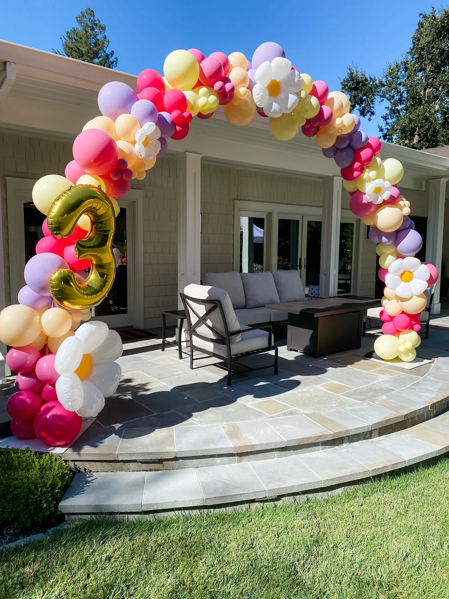 Colorful organic balloon arch with a gold number three at a backyard birthday party