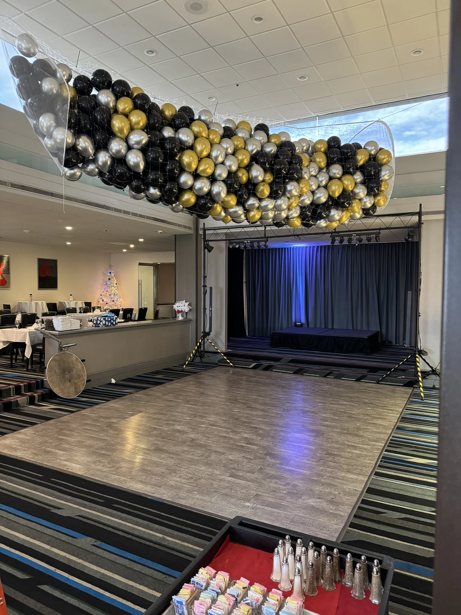 Black, gold and silver balloons held in a suspended drop net above a dance floor
