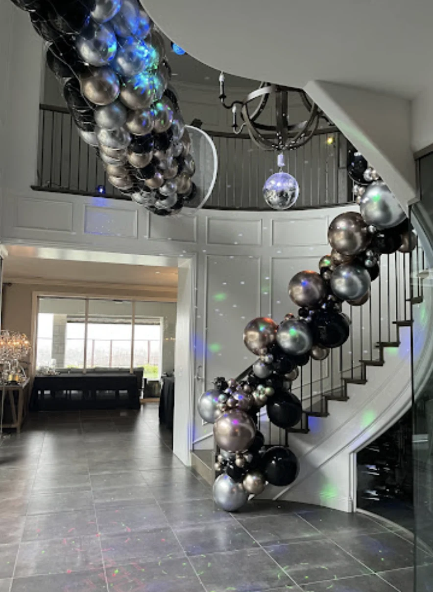 Silver and black balloon drop net suspended above a decorated curved staircase