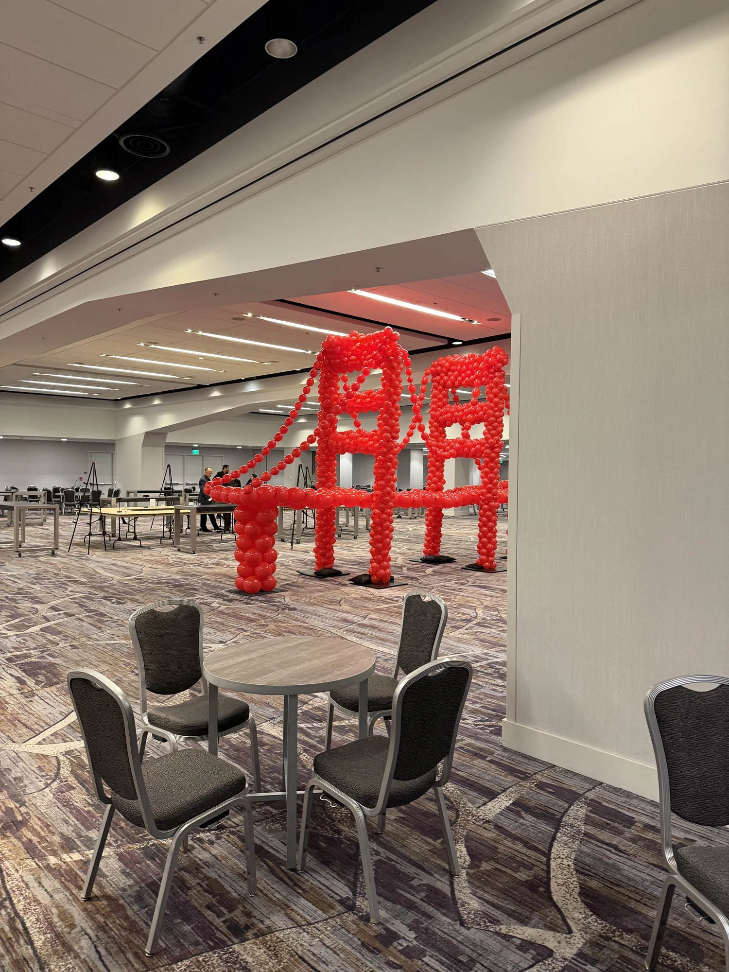 Golden Gate Bridge balloon sculpture viewed through a ballroom opening beside event seating