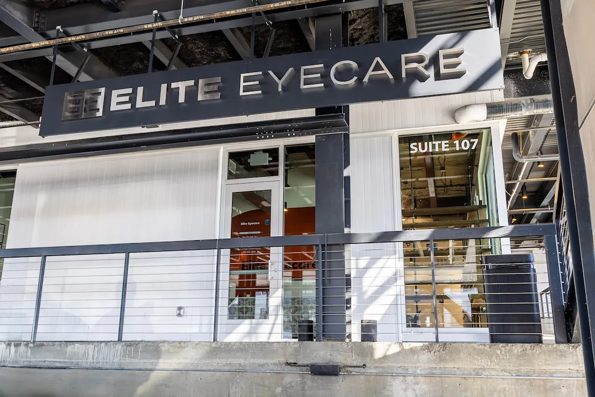 Exterior view of Elite Eyecare office entrance with signage above and suite 107 marked on window.