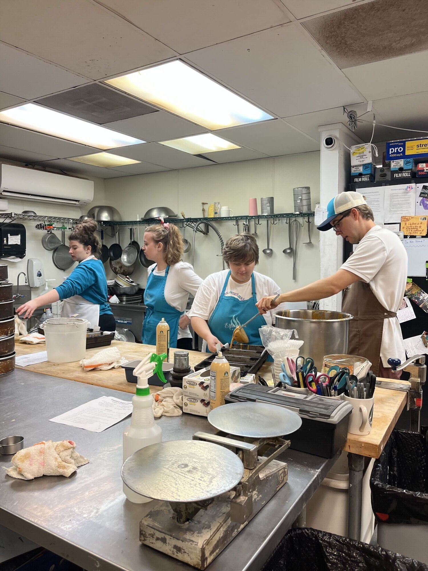 A photo of four adults in aprons cooking in a commercial kitchen.