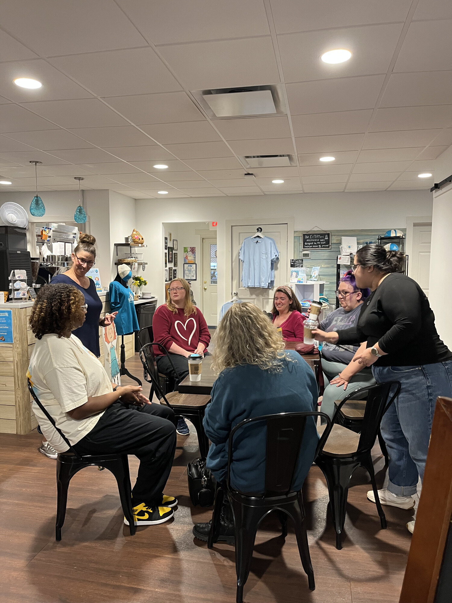 A photo of a group of adults inside Esteamed Coffee learning sign language.