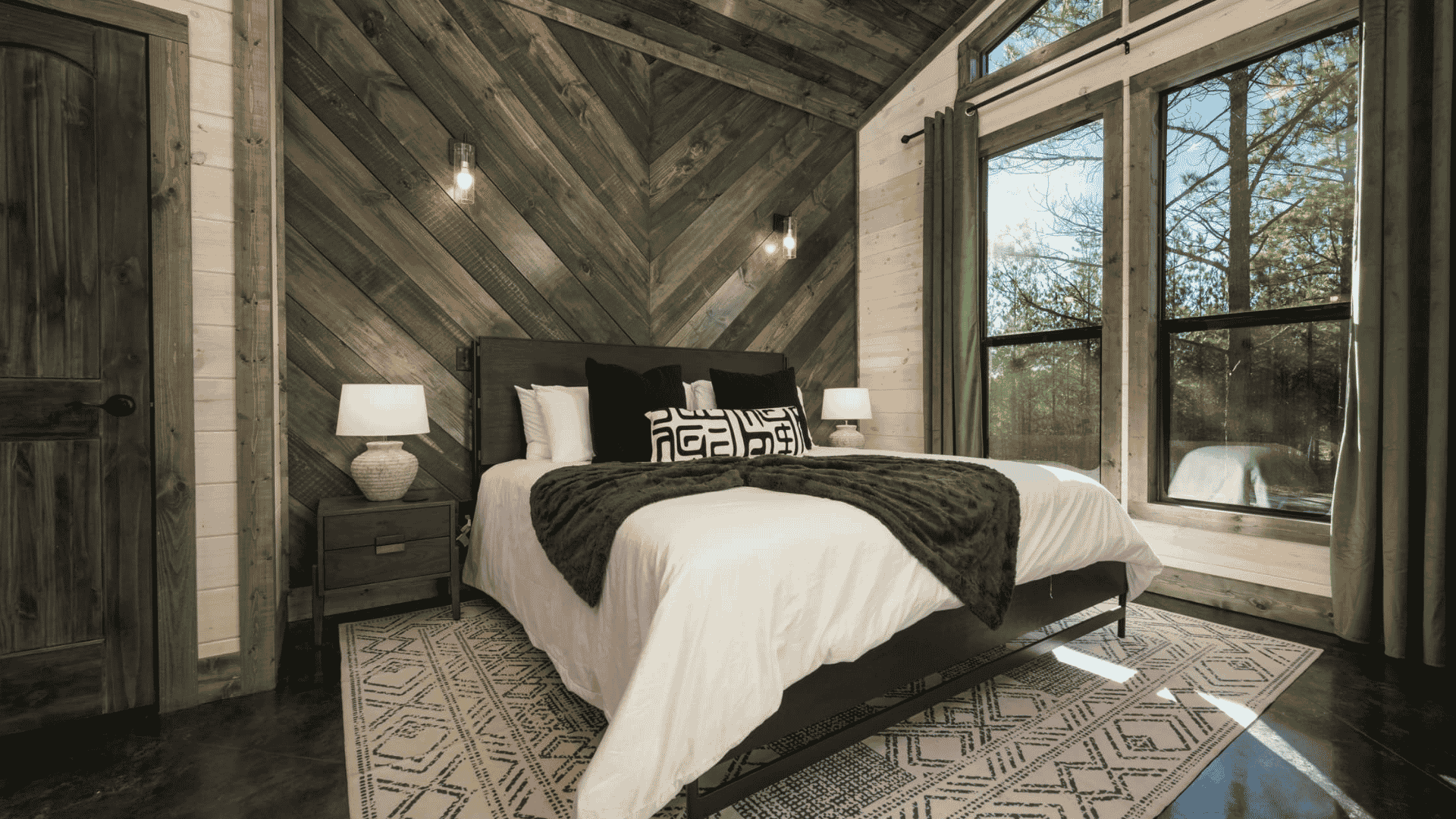 A crisply made bed with white sheets in a dark grey wood bedroom.