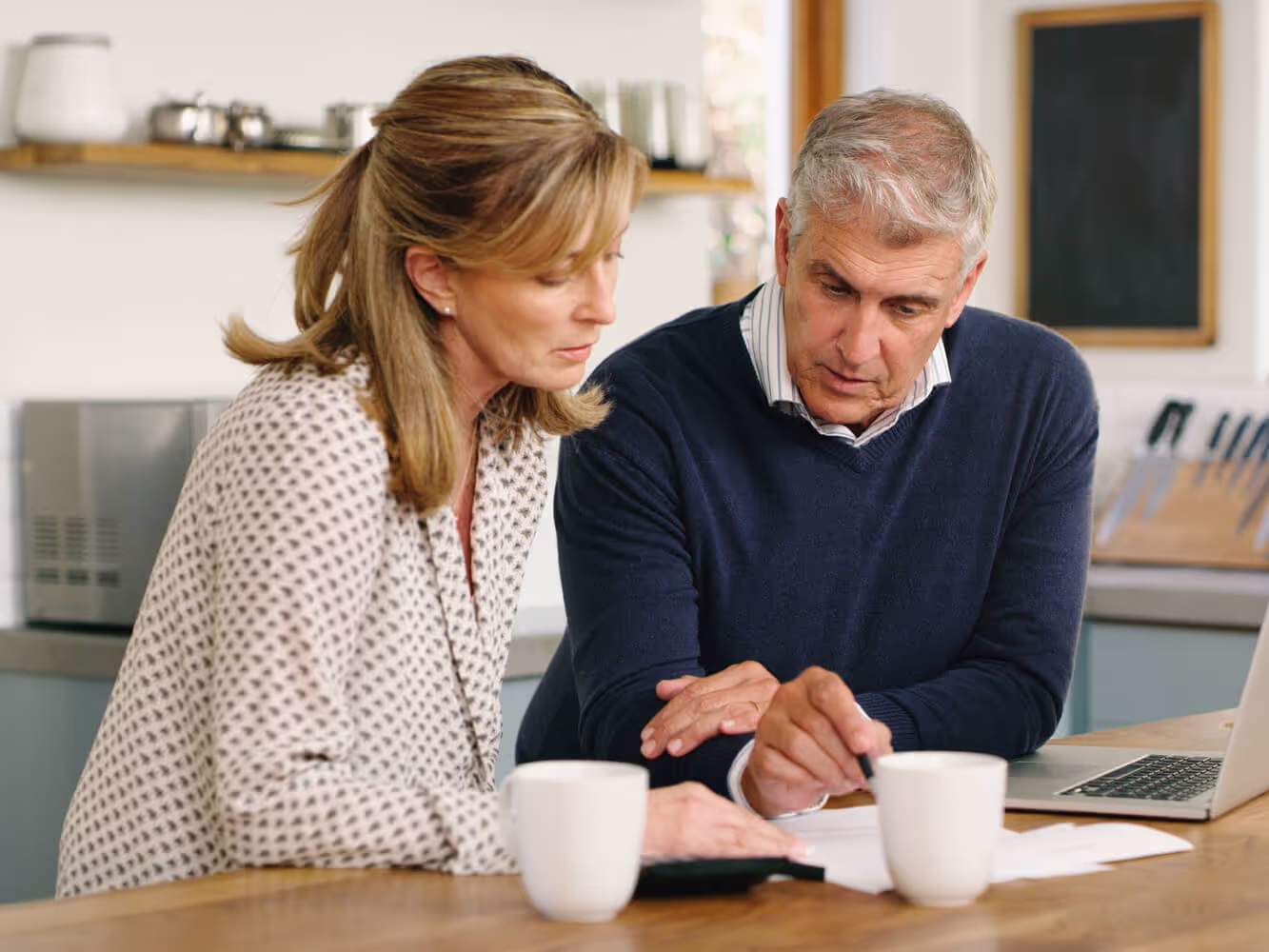 Couple looking very serious reviewing their living wills while seated in their kitchen