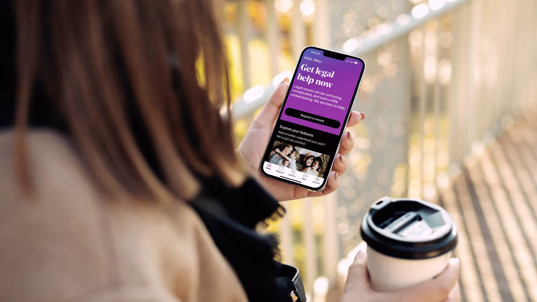 Woman holding a cup of coffee is viewing the LegalShield app on her phone. The screen reads: Get legal help now.