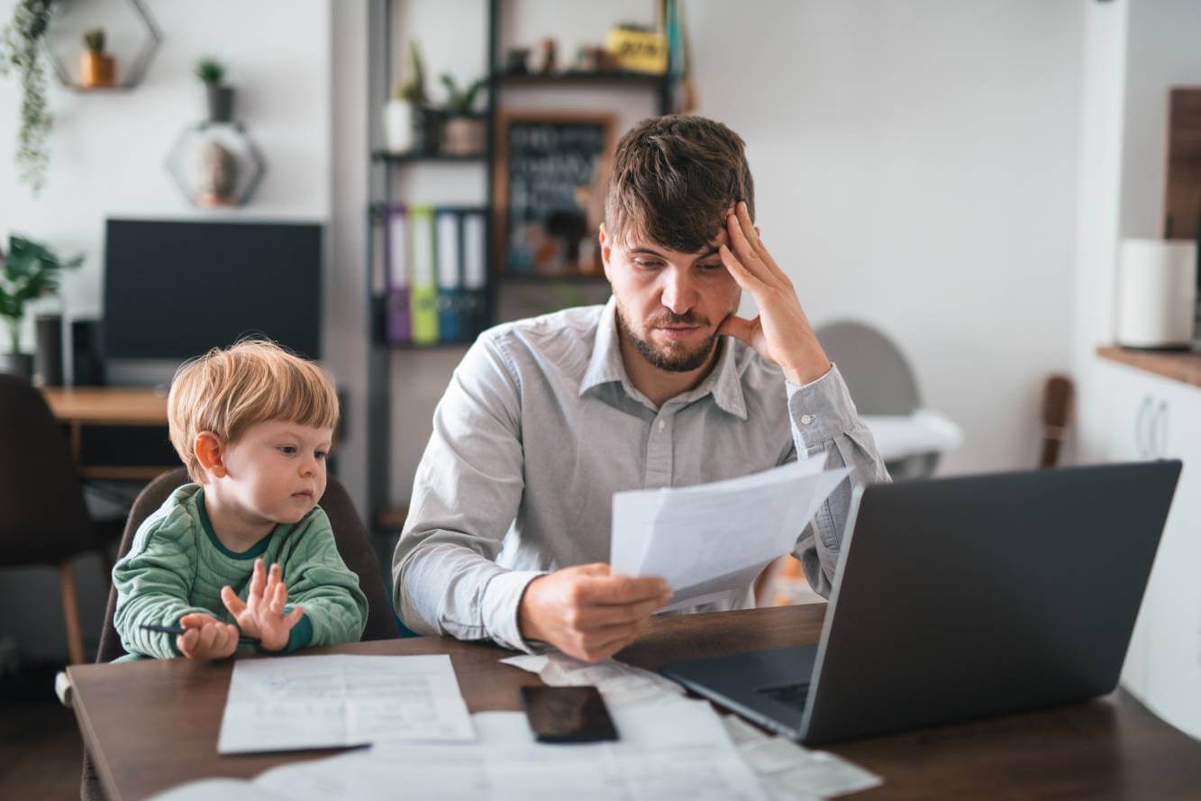 father reviewing homeownership documents sitting at table next to his young son