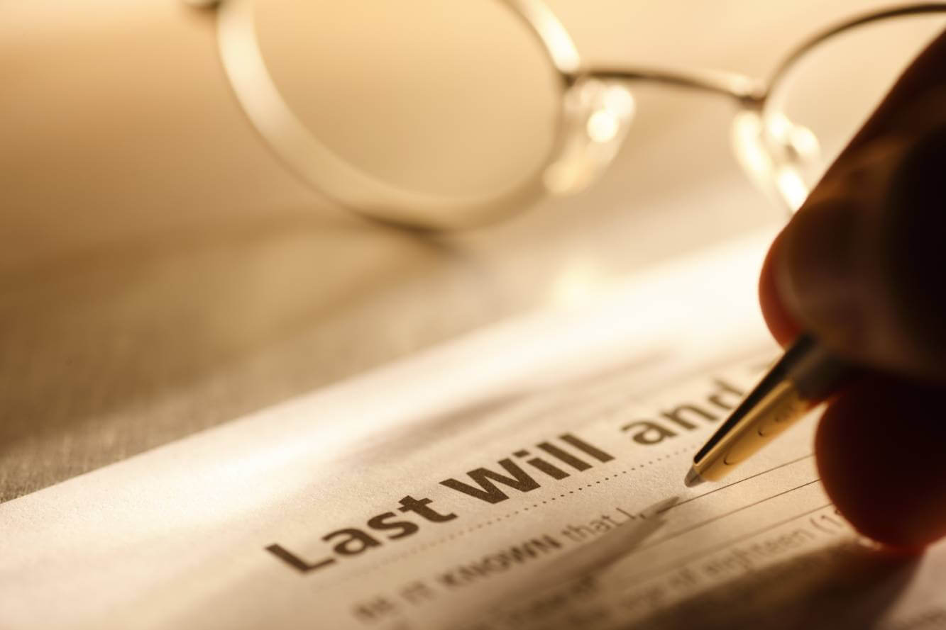 person holding an ink pen to start making a will