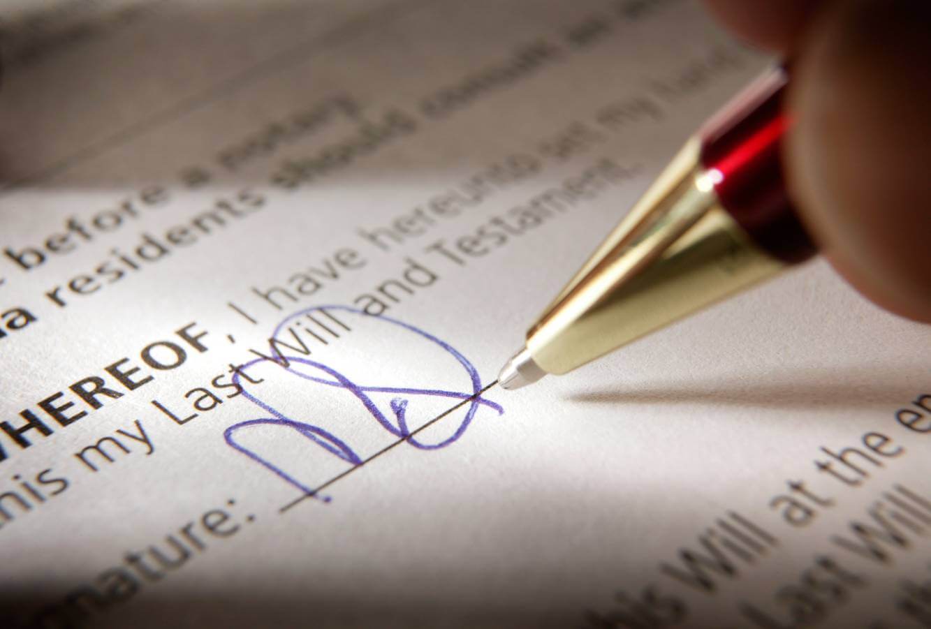 person signing a will with an ink pen