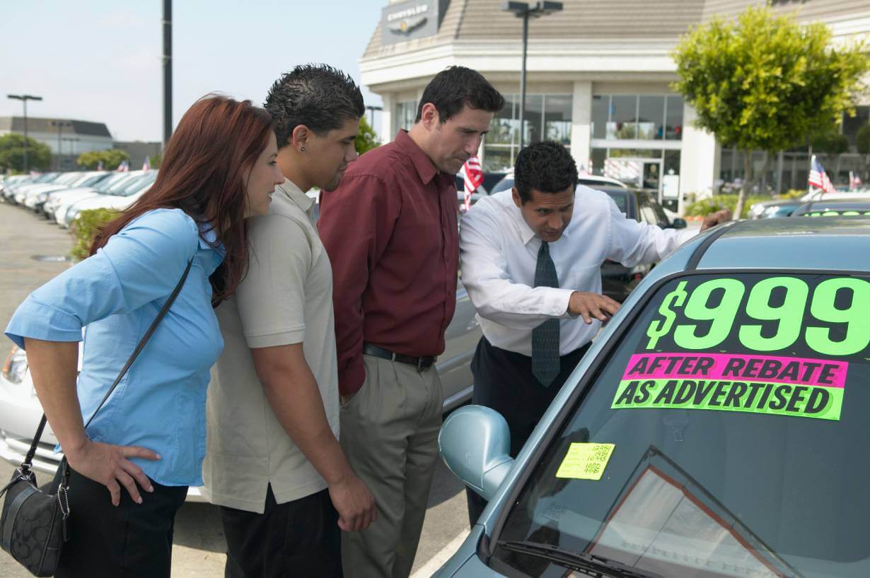 family looking at used car to purchase at a car dealership
