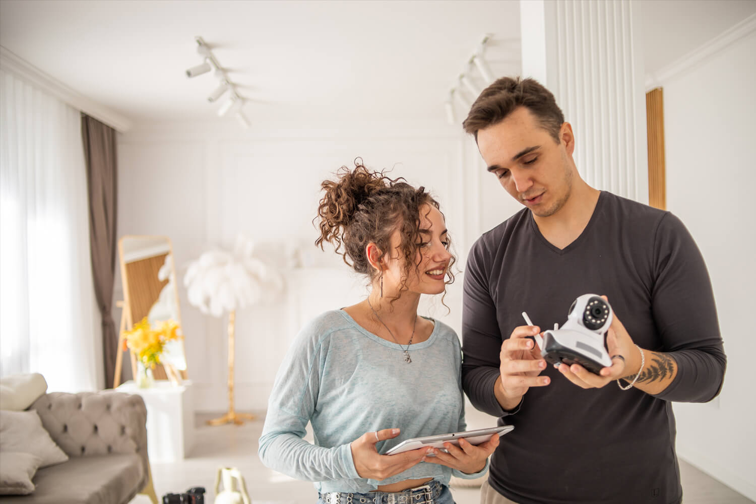 A young couple are setting up a security camera for home surveillance in their apartment