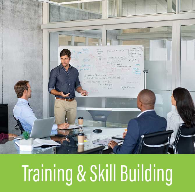 Man giving a presentation with diagrams on a whiteboard to three seated colleagues in a modern office meeting room.