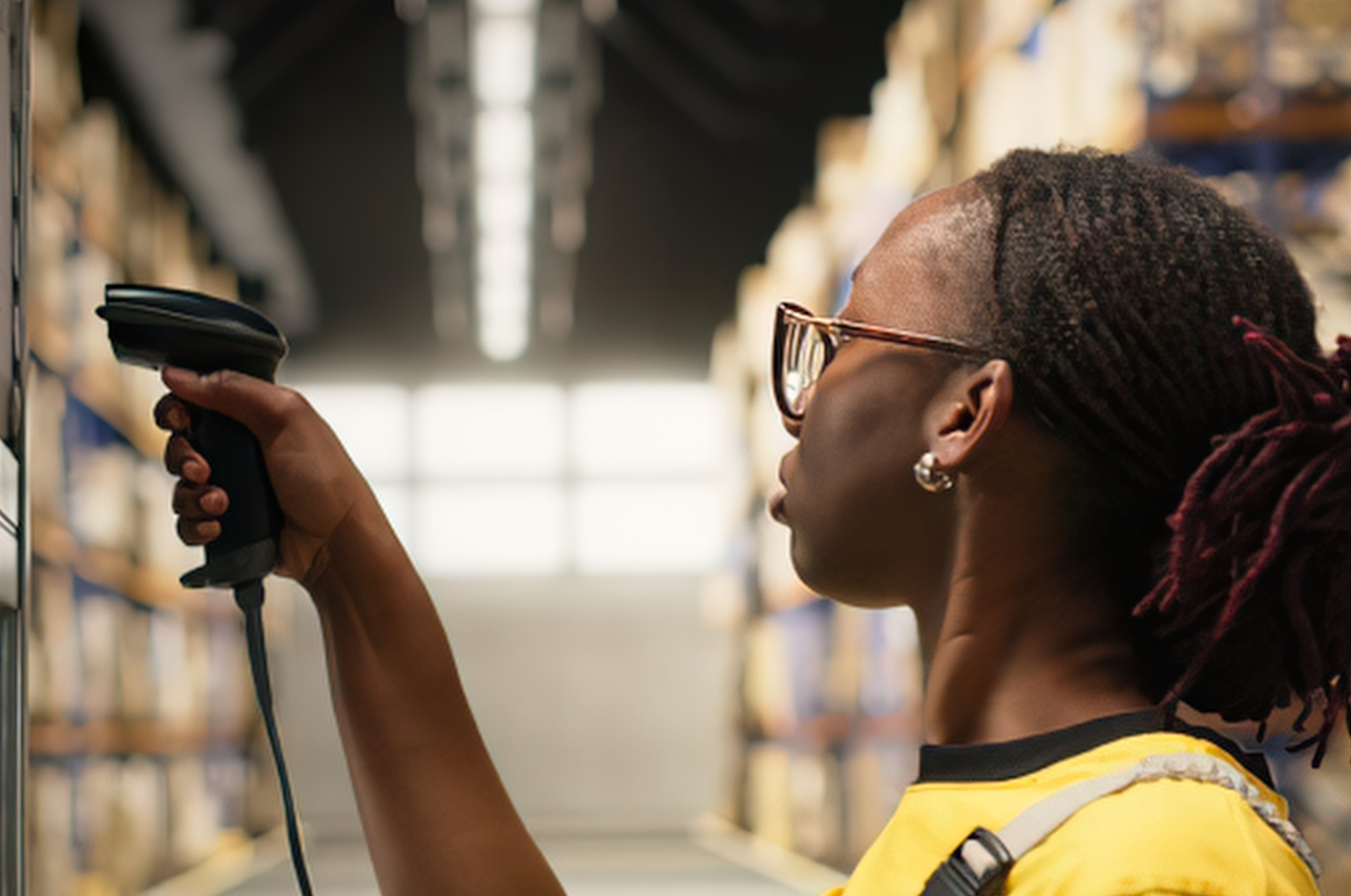 Retail associate using a handheld barcode scanner in a store aisle to complete a frontline task.