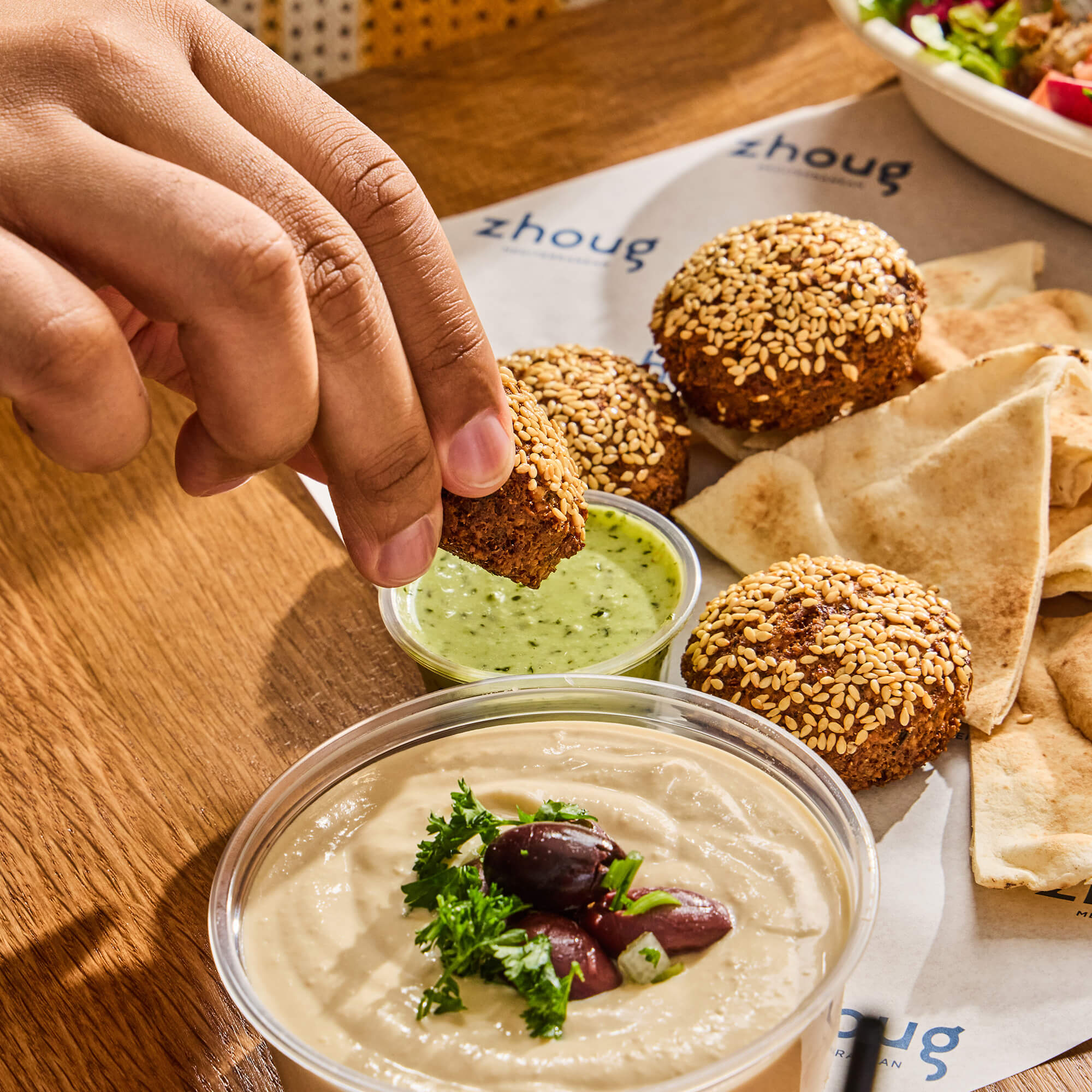 Hungry guest dipping falafel into sauce