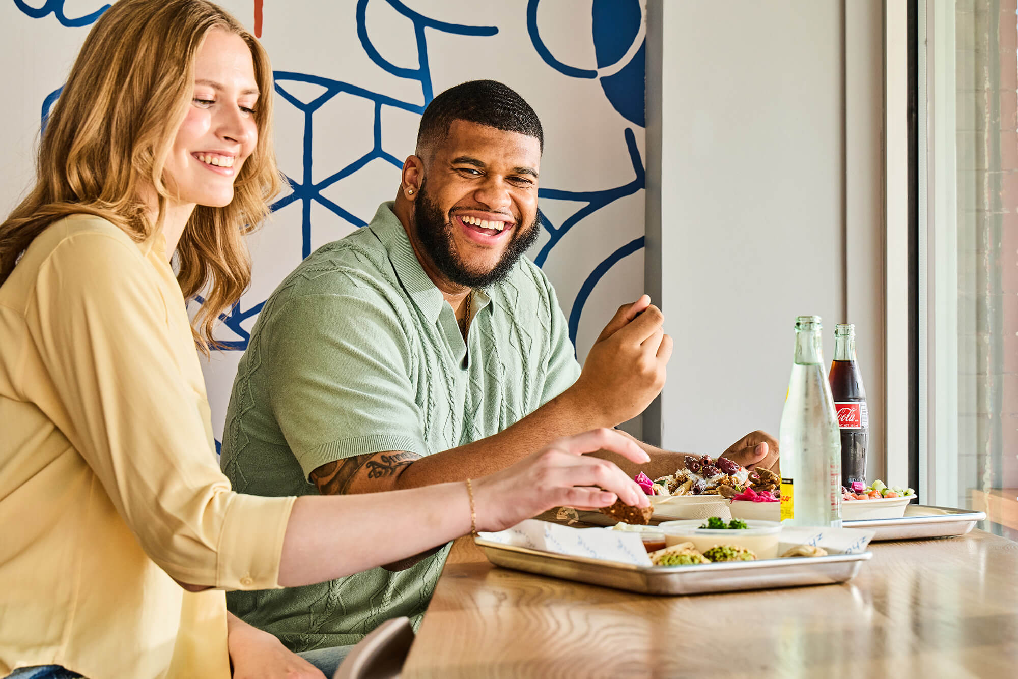 Young woman and young man enjoying their Zhoug Mediterranean food.