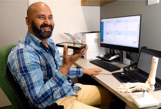 A man with a beard and a blue plaid shirt holding a cell phone.