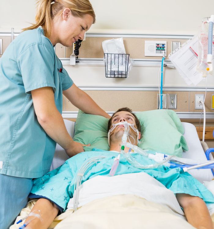 A man in a hospital bed with a nurse attending to him.