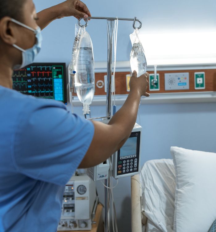 A woman in a blue scrub is checking bag of fluid.