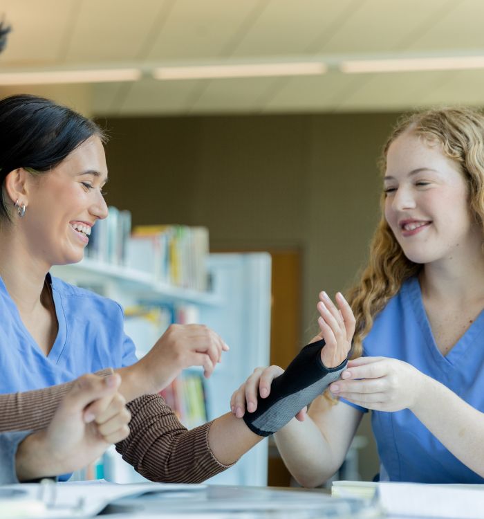 Two women in blue scrubs are smiling at each other