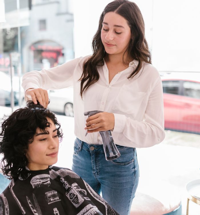 A woman getting her hair blow dried by another woman.